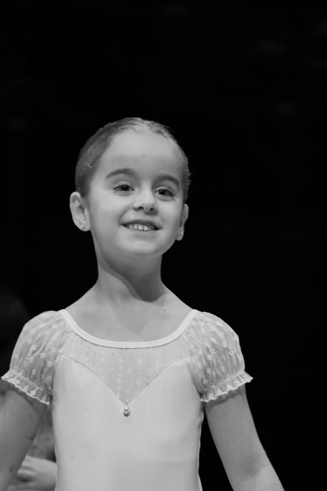 Una alumna pequeña sonriendo sobre el escenario